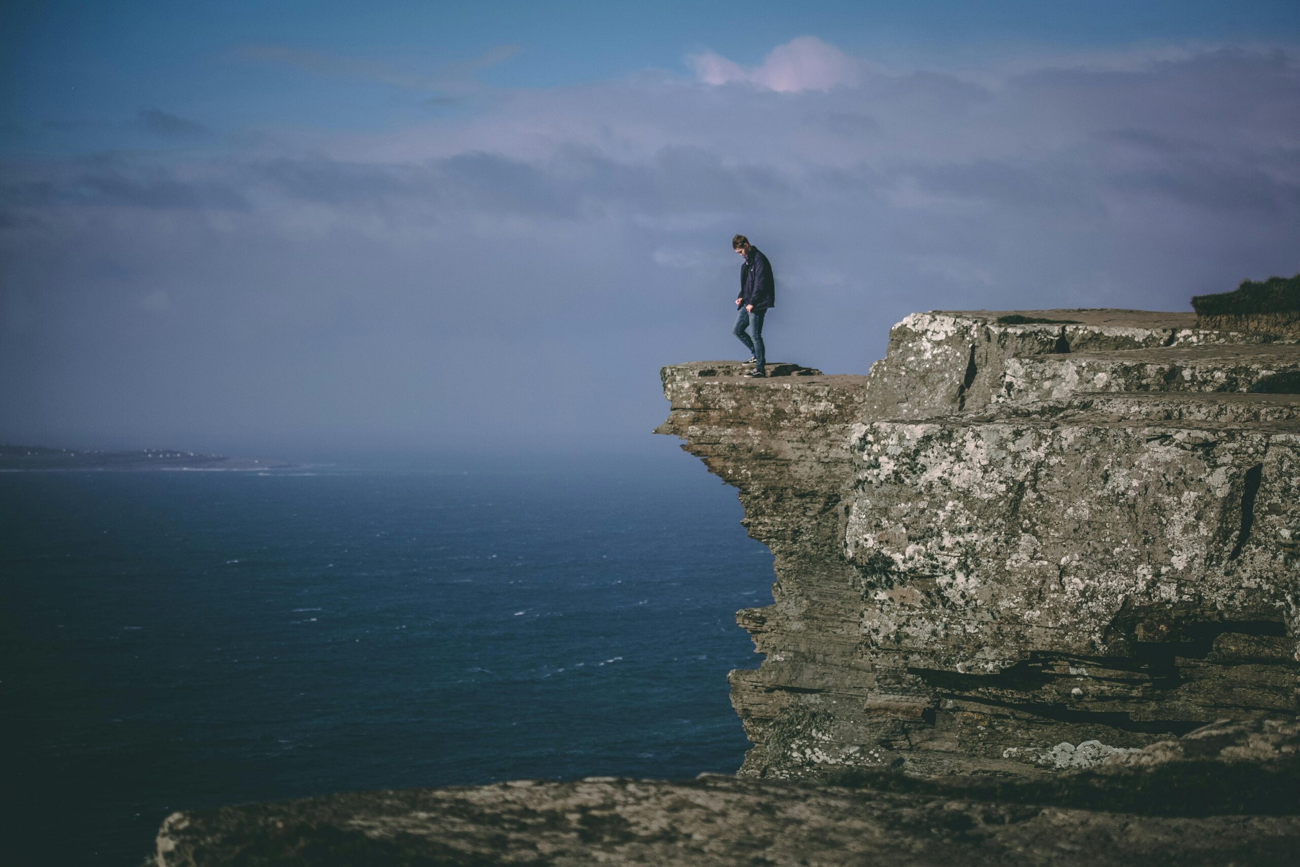Person hesitating on cliff edge symbolizing fear of failure and life decisions